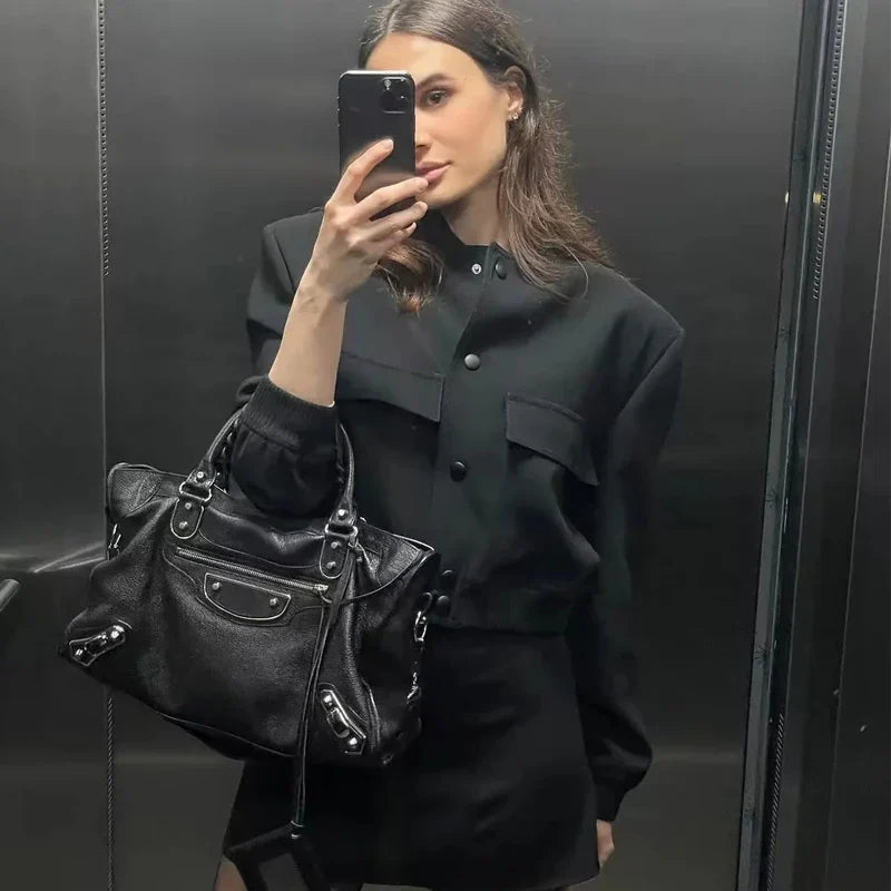 Frau im schwarzen Outfit macht Selfie im Aufzug, trägt schwarze Designer-Handtasche. Mode, Selfie, Aufzug, schwarze Kleidung, Designer-Tasche.