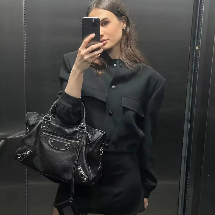 Frau im schwarzen Outfit macht Selfie im Aufzug, trägt schwarze Designer-Handtasche. Mode, Selfie, Aufzug, schwarze Kleidung, Designer-Tasche.