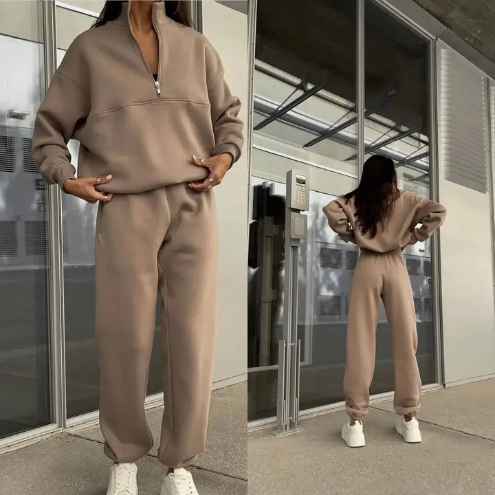 Damen-Sweatshirt und Jogginghose in Beige, lässiger Freizeitlook, moderne Streetwear, bequeme Mode, ideal für Herbst und Winter, vor Glasfassade.