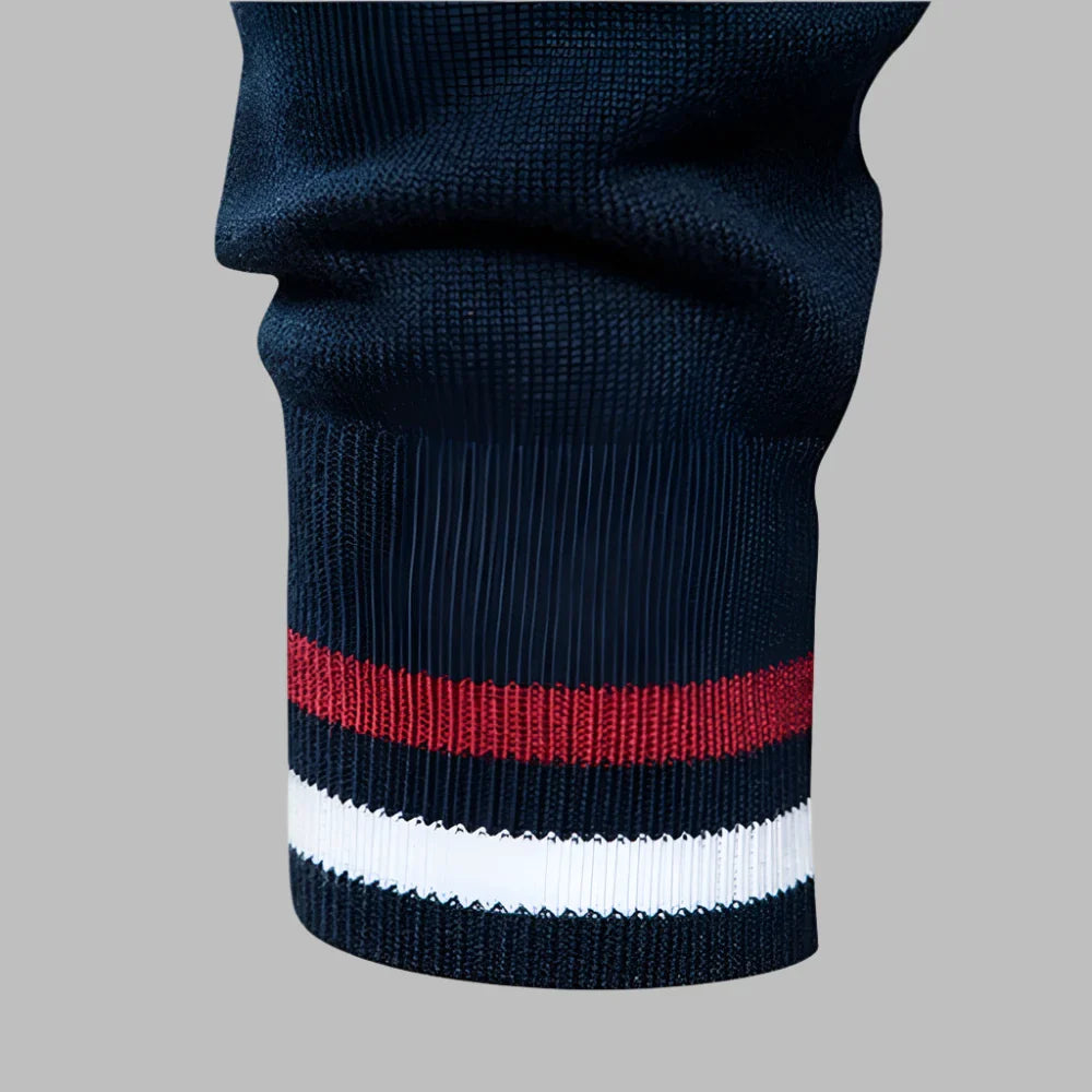 Dunkelblauer Strickärmel mit roten und weißen Streifen, modisches Design, hochwertige Textur, Detailansicht, stilvolle Bekleidung.