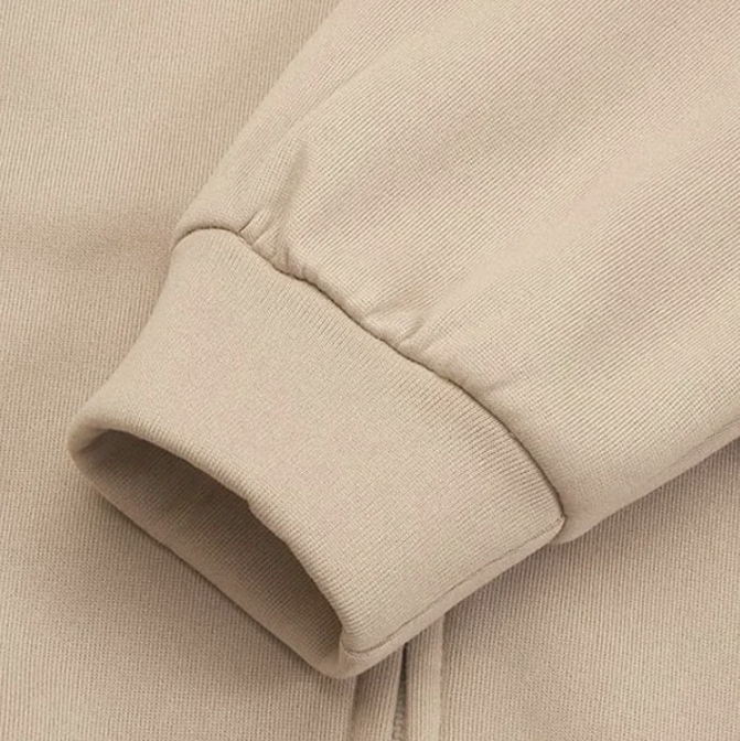 Beiger Sweatshirt-Ärmel aus Baumwolle, Nahaufnahme. Modetrend, bequeme Freizeitkleidung, hochwertige Textur, stilvolles Design.