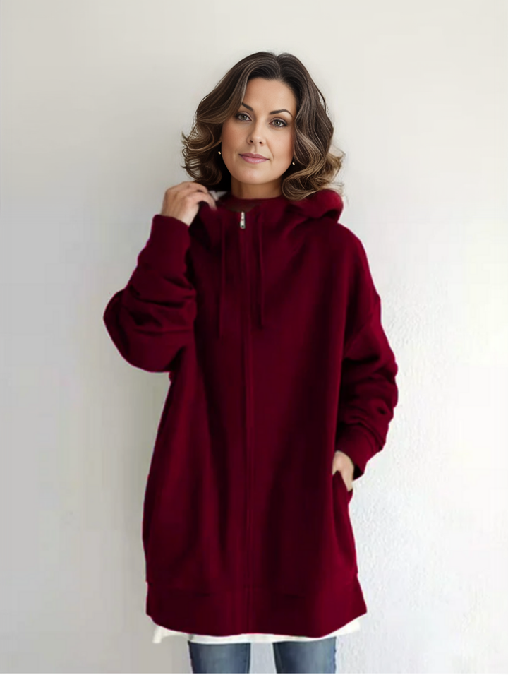 Frau in rotem Kapuzenpullover, lässiger Stil, weiße Wand im Hintergrund, Mode, Herbstkleidung, gemütlicher Look, Damenmode, Freizeitoutfit.