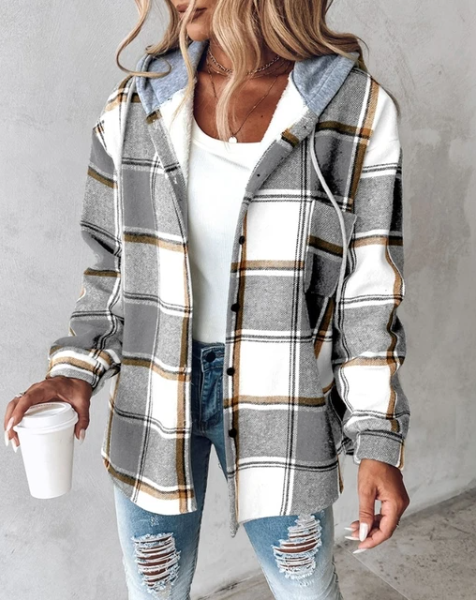Frau in kariertem Hoodie mit Kapuze, weißem Top und zerrissenen Jeans hält Kaffeebecher. Modetrend, lässiger Stil, Streetwear-Look.
