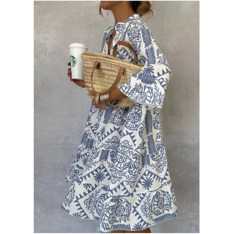 Frau in blau-weiß gemustertem Kleid mit Strohtasche und Starbucks-Becher. Sommermode, Freizeitkleidung, Boho-Stil.