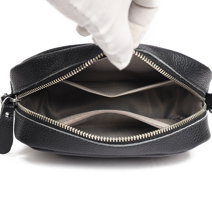 Schwarze Lederhandtasche mit geöffneter Reißverschluss, zeigt Innenfächer. Hochwertige Damenmode, stilvolles Accessoire, elegantes Design.