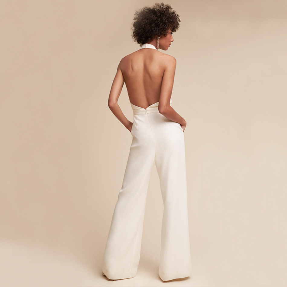 Rückenansicht einer Frau in einem eleganten, weißen, rückenfreien Jumpsuit vor beigem Hintergrund. Mode, Damenbekleidung, stilvoller Look.