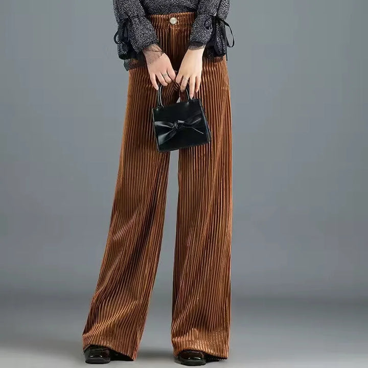 Braune, weit geschnittene Cordhose kombiniert mit schwarzer Handtasche und grauem Oberteil. Modetrend, Damenbekleidung, Herbstmode.