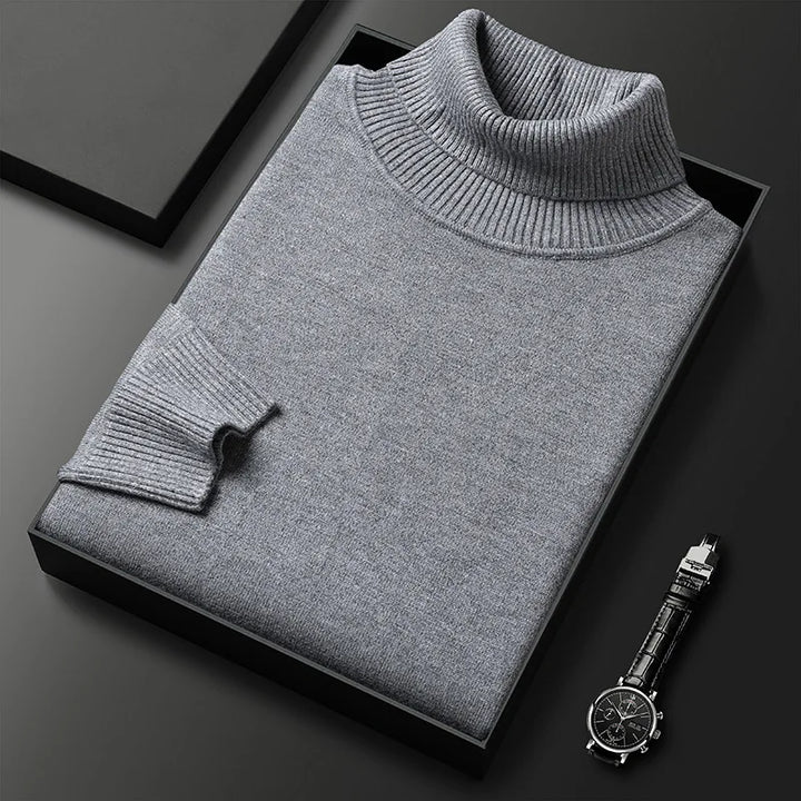 Grauer Rollkragenpullover aus Kaschmir in Geschenkbox auf schwarzem Hintergrund, neben einer eleganten Armbanduhr. Luxuriöse Herrenmode.
