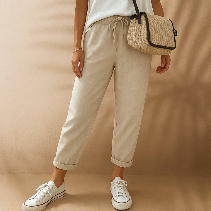 Damen in beiger Leinenhose und weißen Sneakers, trägt eine Strohtasche. Modetrend, lässiger Sommerlook, bequeme Freizeitkleidung.