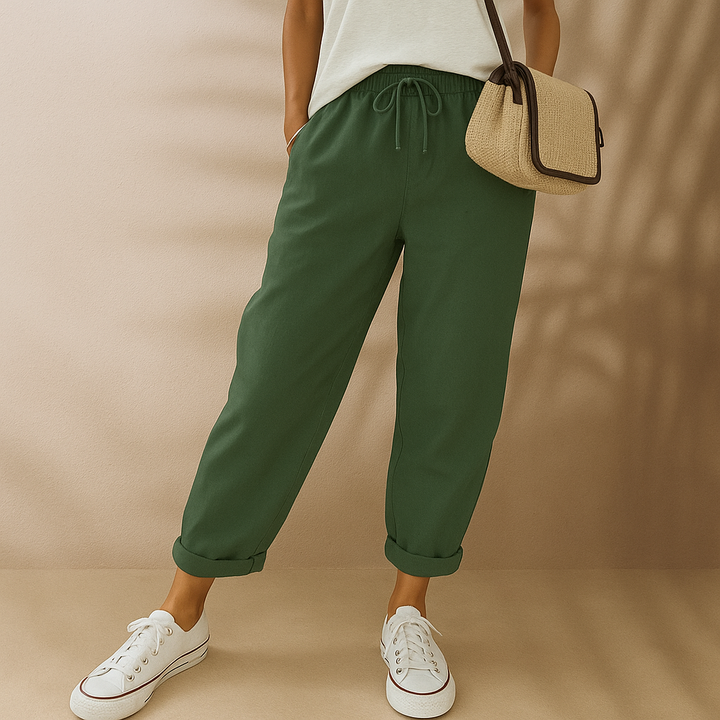 Dame in grüner Jogginghose, weißem T-Shirt und weißen Sneakers, trägt eine beige Umhängetasche. Modetrend, lässiger Stil, bequeme Kleidung.