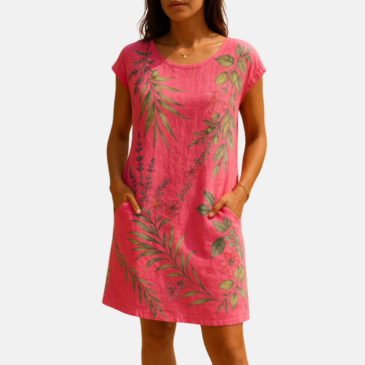 Frau in pinkem Sommerkleid mit floralen Mustern, kurzen Ärmeln und Taschen. Perfekt für Freizeitmode und Sommeroutfits.