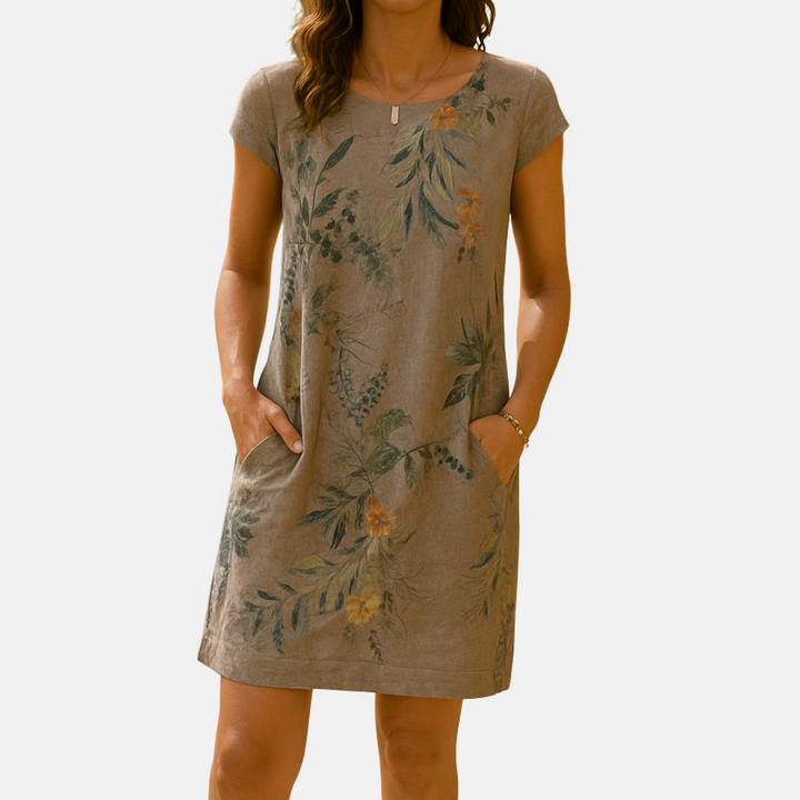 Frau trägt ein sommerliches, knielanges Kleid mit floralen Mustern und kurzen Ärmeln. Perfekt für Freizeitmode und sommerliche Anlässe.