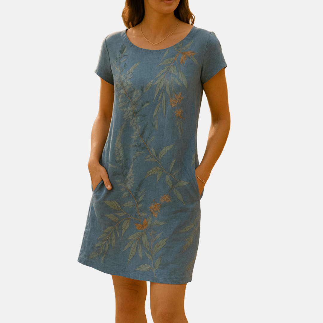 Frau in blauem Leinenkleid mit floralen Mustern, kurzen Ärmeln und Taschen. Sommermode, nachhaltige Kleidung, elegantes Design.