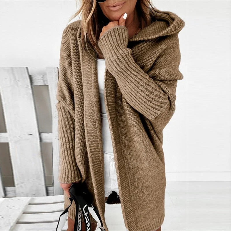 Frau in beigem Strickcardigan, vor weißem Hintergrund. Modischer Oversize-Pullover, Herbst-Winter-Trend, gemütlicher Look.