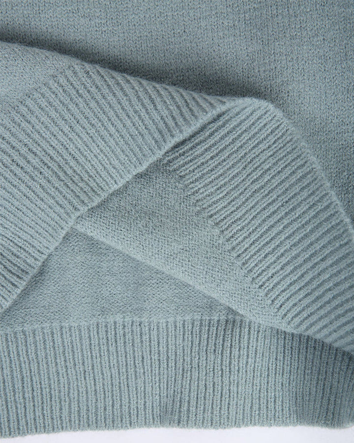 Grauer Strickpullover aus weicher Wolle, Nahaufnahme der Textur und des gerippten Saums. Hochwertige Wintermode, gemütlicher Strickstoff.
