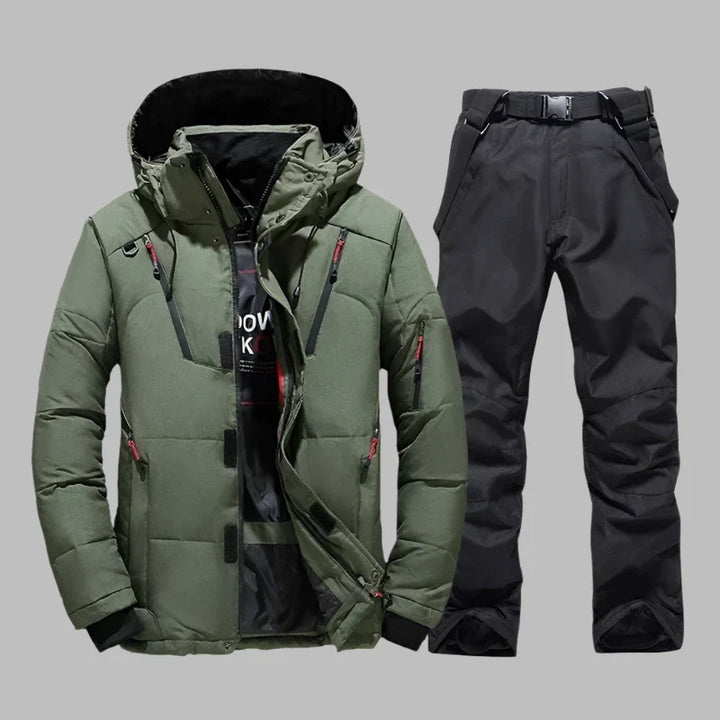 Grüne Winterjacke mit Kapuze und schwarze Skihose auf grauem Hintergrund. Outdoor-Bekleidung, wasserdicht, warm, ideal für Wintersport.