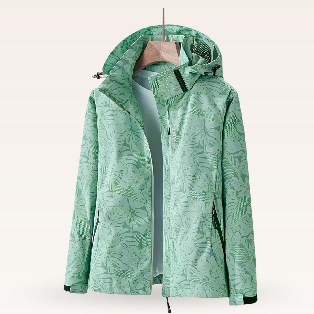 Grüne Damenjacke mit tropischem Blattmuster, Kapuze und Reißverschluss, ideal für Outdoor-Aktivitäten. Modische, funktionale Freizeitbekleidung.