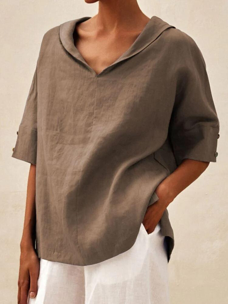 Damenmode: Lockeres, braunes Leinenhemd mit V-Ausschnitt und 3/4-Ärmeln, kombiniert mit weißer Hose. Eleganter, minimalistischer Stil.