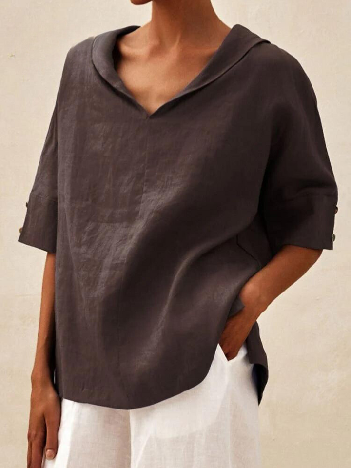 Damenbluse aus Leinen in Dunkelbraun, lockerer Schnitt, V-Ausschnitt, halblange Ärmel, kombiniert mit weißer Hose. Ideal für Sommermode.