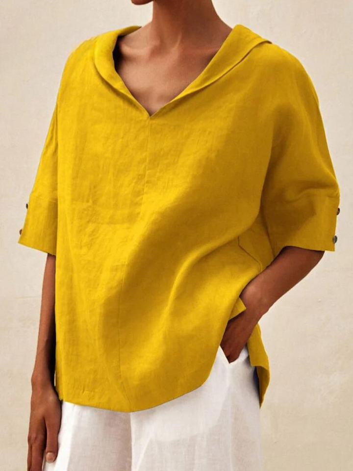 Gelbe Leinenbluse mit V-Ausschnitt und halblangen Ärmeln, kombiniert mit weißer Hose. Modetrend, Sommeroutfit, Damenbekleidung.