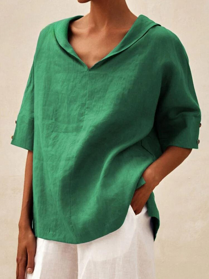 Person trägt grüne Leinenbluse mit V-Ausschnitt und weißen Hosen. Modetrend, nachhaltige Kleidung, lässiger Stil, Sommeroutfit.