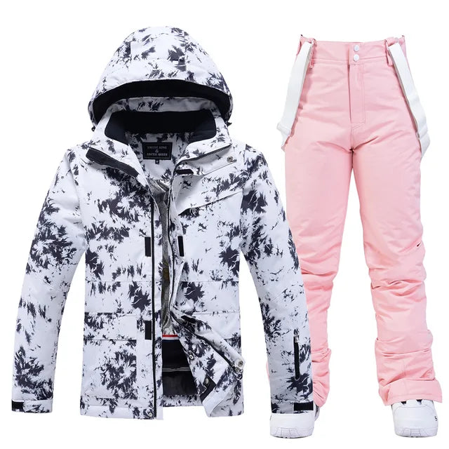 Weiße Skijacke mit schwarzem Muster und rosa Skihose für Damen. Winterbekleidung, wasserdicht, atmungsaktiv, ideal für Skifahren und Snowboarden.
