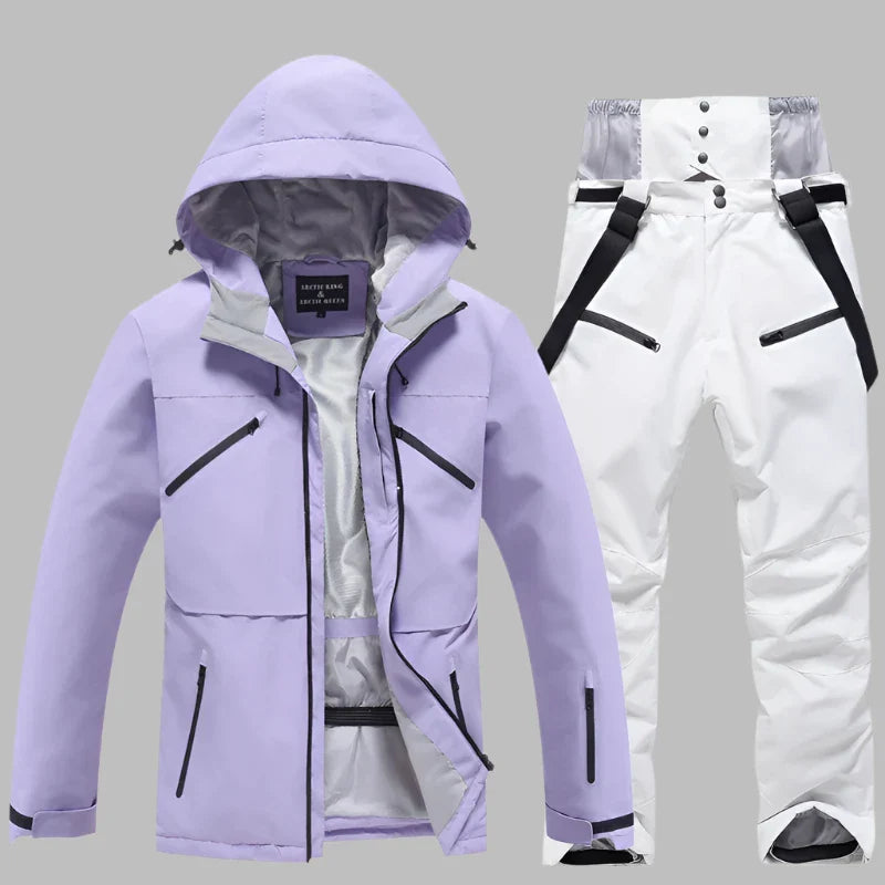 Lila Skijacke mit Kapuze und weiße Skihose mit Hosenträgern auf grauem Hintergrund. Winterbekleidung, Outdoor, wasserdicht, atmungsaktiv.