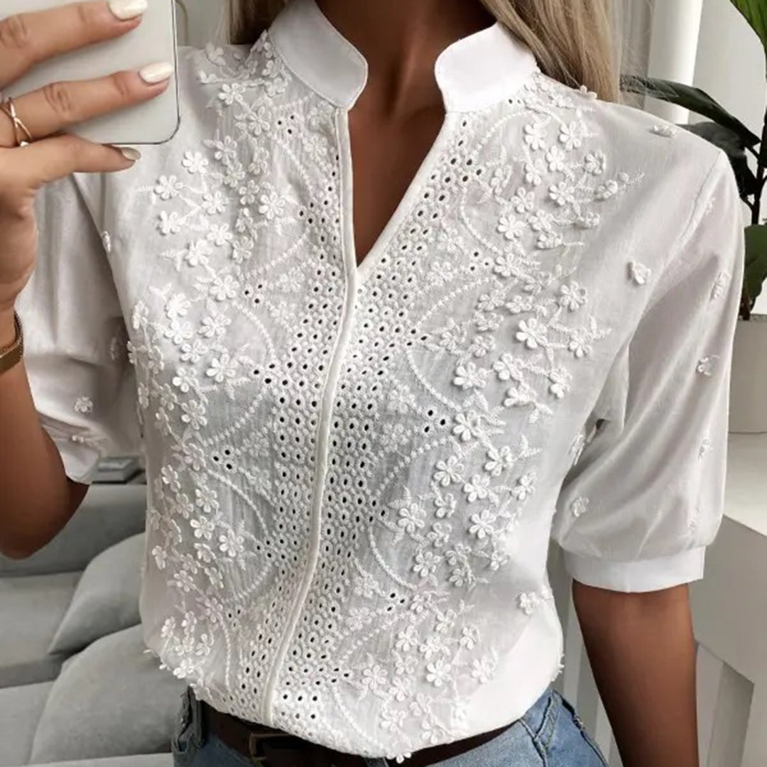 Weiße Bluse mit floraler Stickerei und Lochmuster, elegantes Design, kurzärmlig, ideal für Sommermode und stilvolle Outfits.