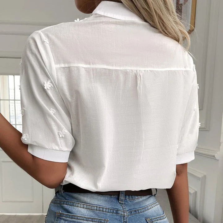 Frau in weißer, bestickter Bluse und blauer Jeans von hinten. Modetrend, Sommeroutfit, elegante Damenbekleidung.