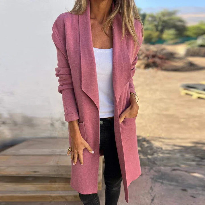 Frau in rosa Strickjacke, weißem Top und schwarzer Hose im Freien. Modischer Herbst-Look, lässiger Stil, Damenmode.