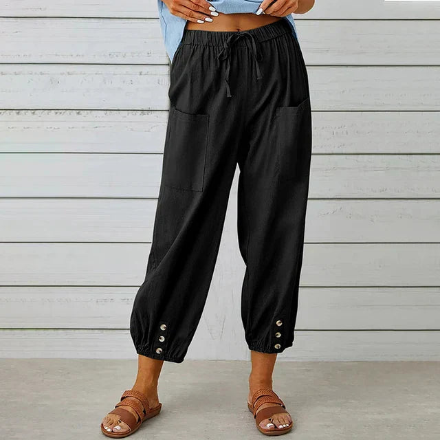 Damenhose in Schwarz mit Taschen und Knopfleiste am Saum, kombiniert mit Sandalen. Bequeme Sommermode, lässiger Stil, ideal für Freizeitoutfits.