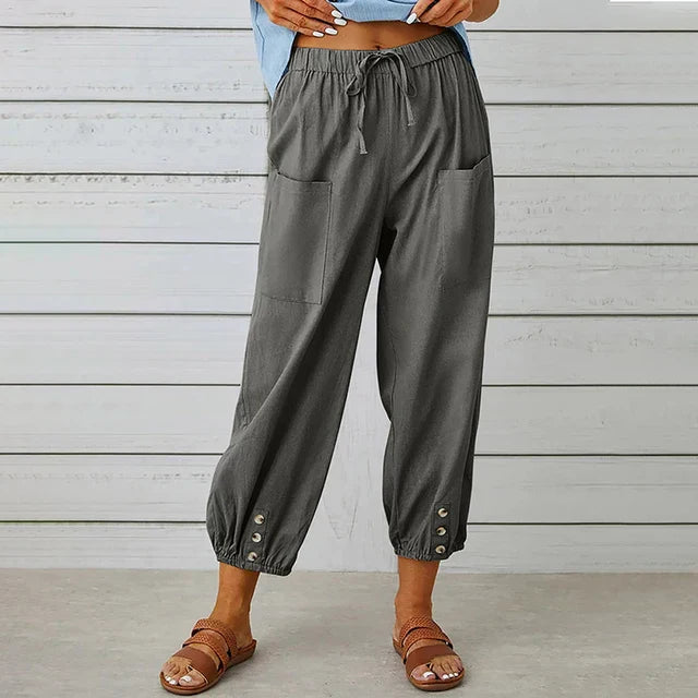 Graue Damenhose mit Taschen und Knöpfen am Saum, kombiniert mit braunen Sandalen. Bequeme Sommermode, lässiger Stil, ideal für Freizeitkleidung.