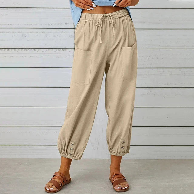 Damenhose beige, lässig, mit Taschen und Knöpfen am Saum, kombiniert mit Sandalen. Perfekt für Sommermode und Freizeitoutfits.