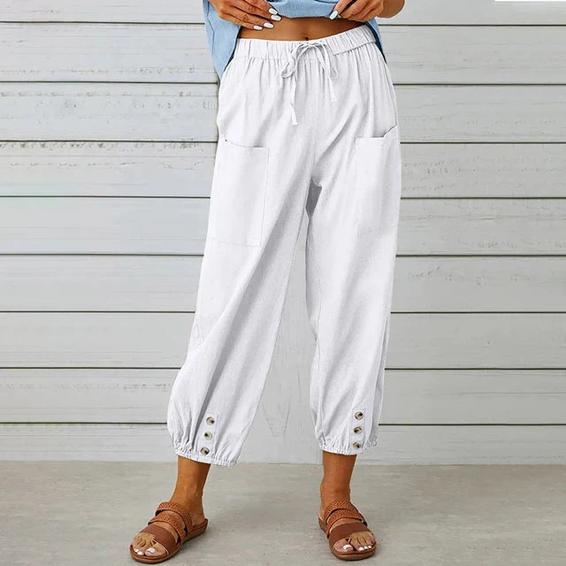 Weiße Damen-Leinenhose mit Taschen und Knöpfen, kombiniert mit braunen Sandalen. Sommermode, lässiger Stil, ideal für warme Tage.