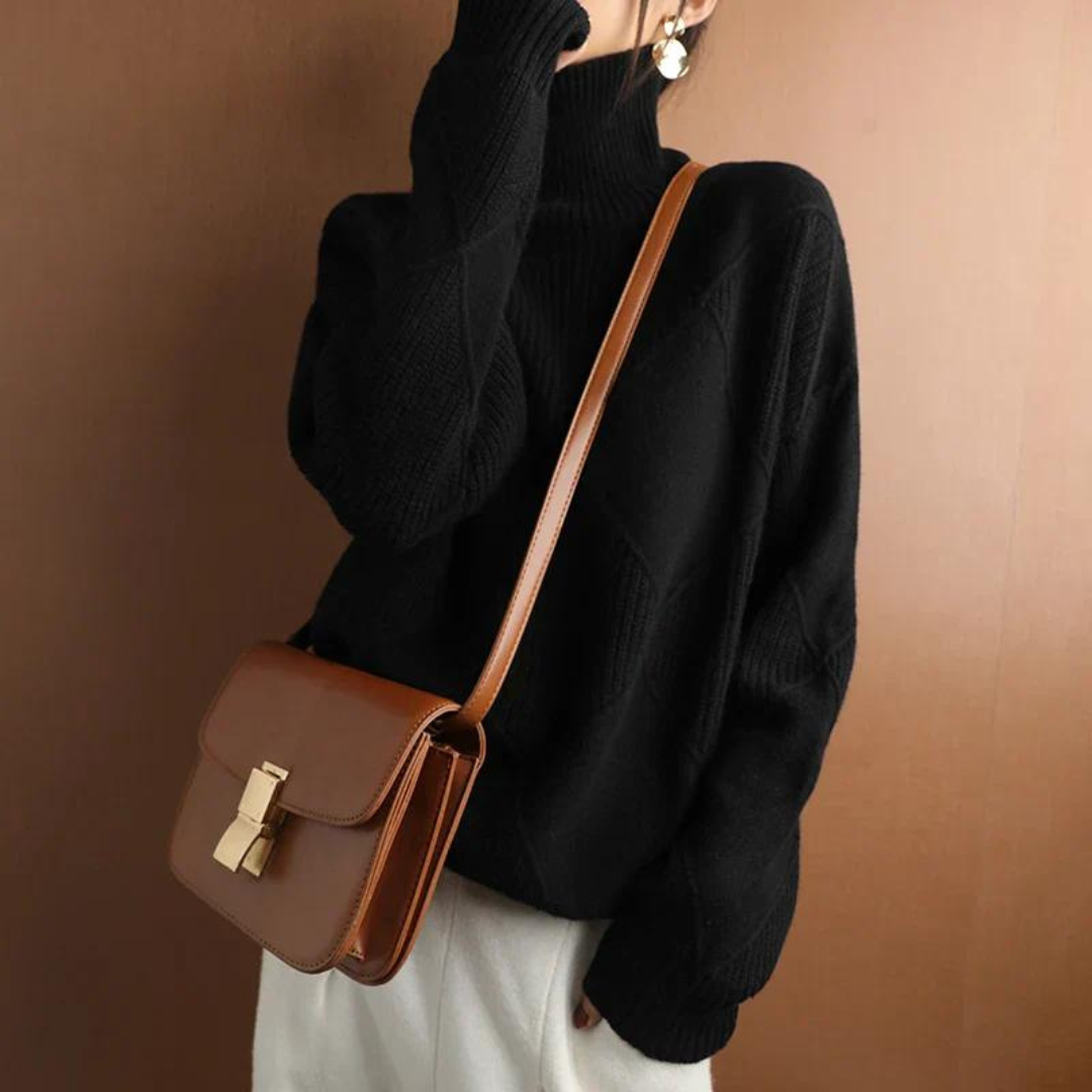 Frau in schwarzem Rollkragenpullover mit brauner Ledertasche, goldener Schnalle, vor braunem Hintergrund. Modetrend, Herbstmode, Damenaccessoires.