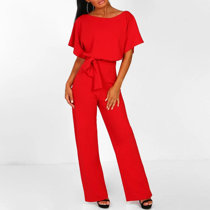 Frau in rotem Jumpsuit mit Gürtel, weiten Hosenbeinen und schwarzen High Heels. Modetrend, Damenbekleidung, eleganter Look.
