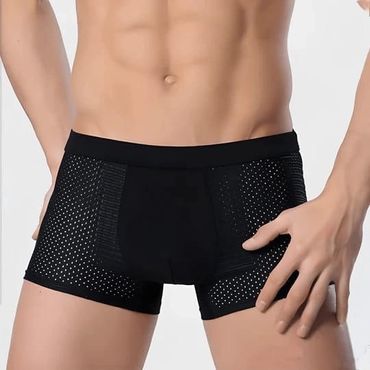 Mann in schwarzer, atmungsaktiver Boxershorts mit Punktmuster, zeigt muskulösen Oberkörper. Herrenunterwäsche, komfortabel, modern.