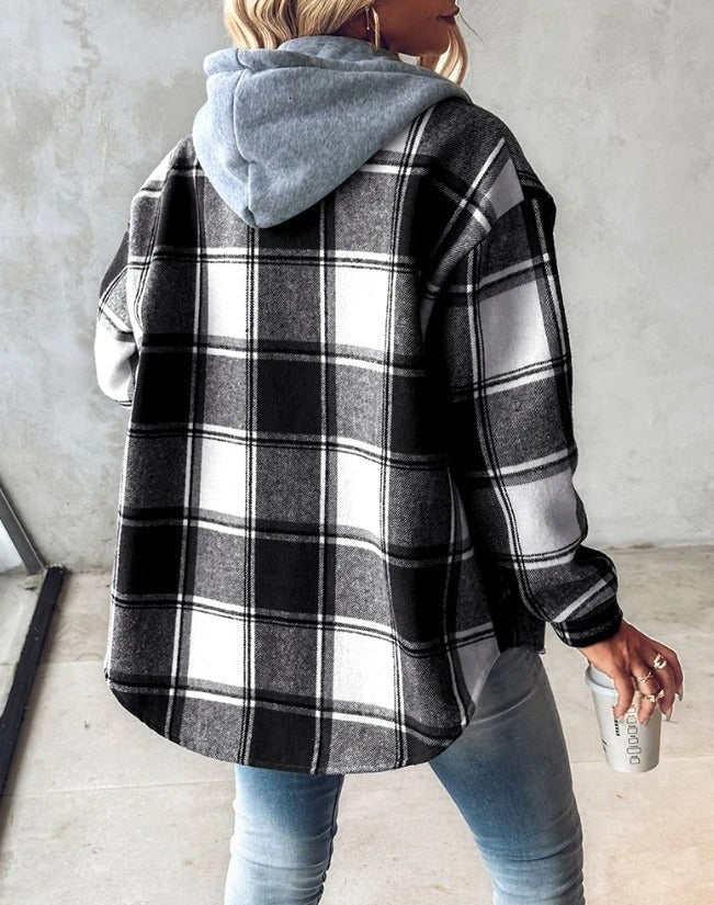 Frau in kariertem Hemd mit grauer Kapuze, hält Kaffeebecher. Modetrend Herbst, lässiger Streetstyle, gemütlicher Look, Damenmode.
