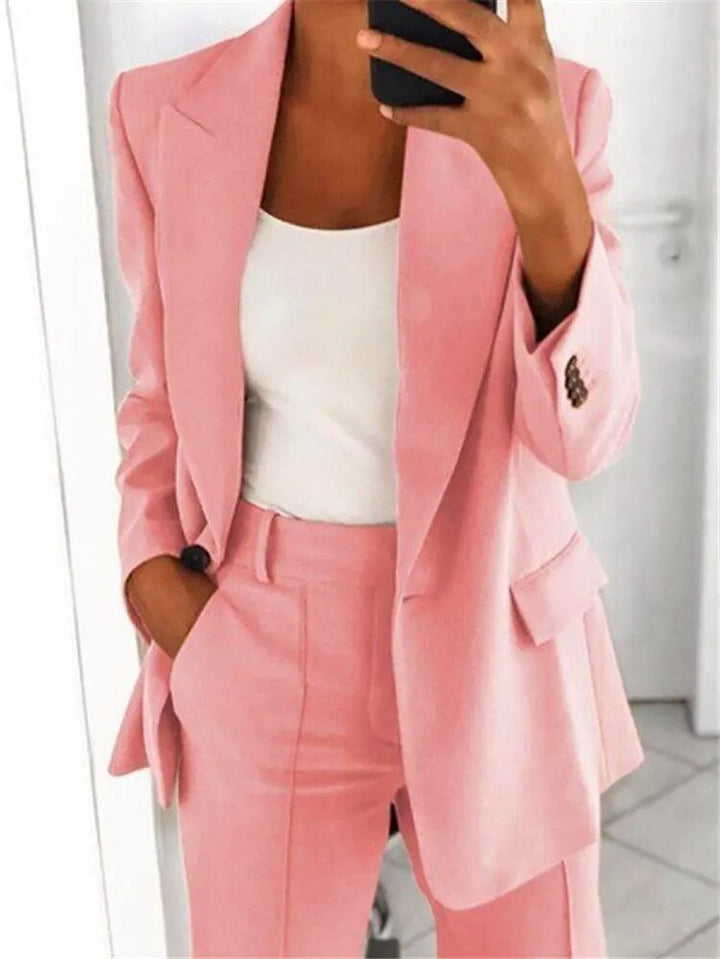 Frau in rosa Anzug mit weißem Top, hält Smartphone. Moderner Business-Look, elegante Damenmode, stilvolle Büro-Outfits.