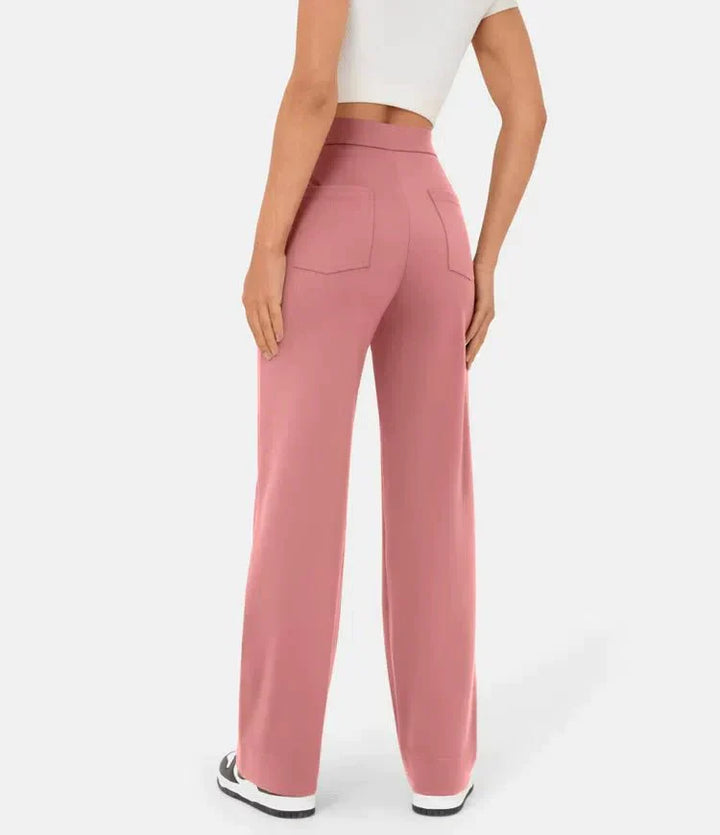 Frau in rosa, weit geschnittener Hose und weißem Crop-Top, Rückansicht. Modetrend, Damenbekleidung, lässiger Stil, bequeme Passform.