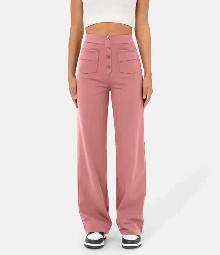 Frau trägt rosa Schlaghose mit hoher Taille und Knopfleiste, kombiniert mit weißem Crop-Top und schwarzen Sneakers. Modetrend, Damenbekleidung.