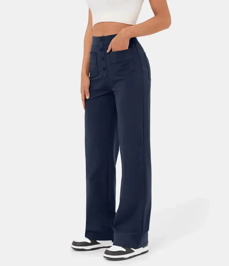 Frau trägt dunkelblaue, weite Hose mit Knöpfen und Taschen, kombiniert mit weißem Top und Sneakers. Modetrend, Damenbekleidung, lässiger Stil.