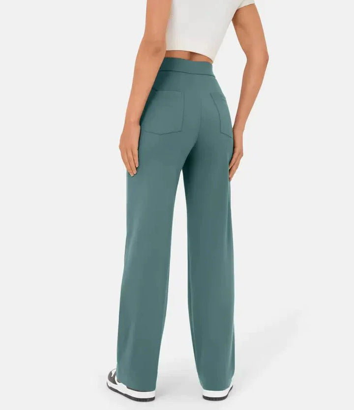 Frau in grüner, weit geschnittener Hose und weißem Crop-Top, Rückansicht. Modetrend, Damenbekleidung, bequeme Freizeitmode, stilvolle Hosen.