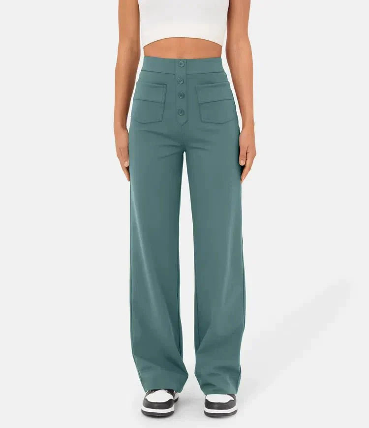 Frau in blauer, weit geschnittener Hose mit hoher Taille und Knöpfen, trägt weißes Crop-Top und schwarze Sneaker. Modetrend, Damenbekleidung.