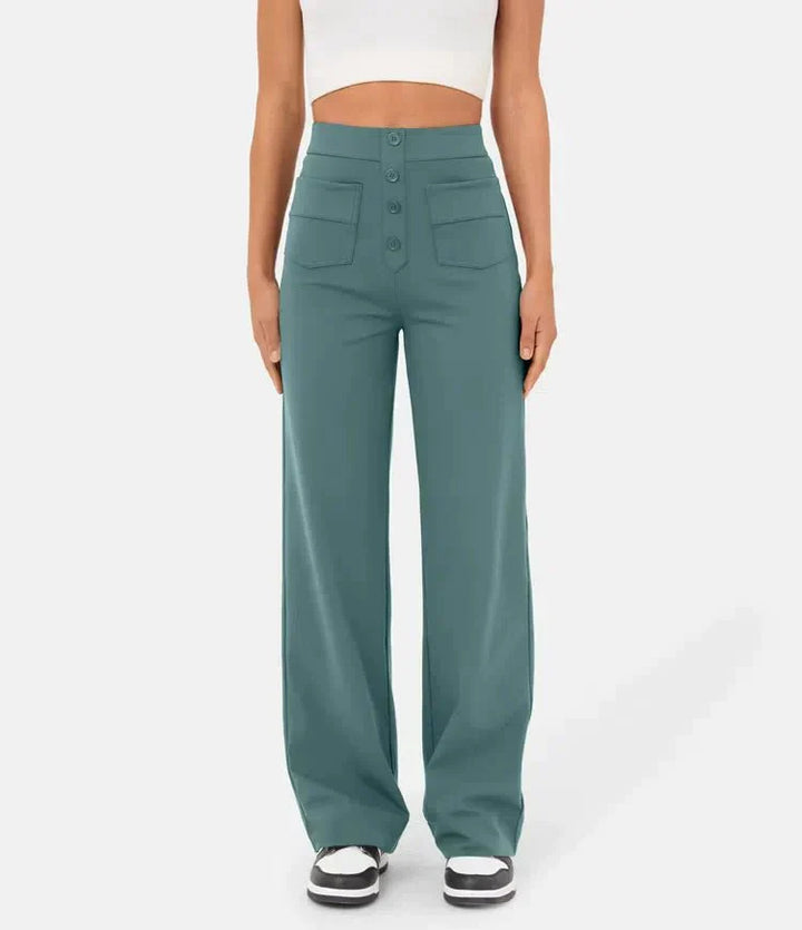 Frau in blauer, weit geschnittener Hose mit hoher Taille und Knöpfen, trägt weißes Crop-Top und schwarze Sneaker. Modetrend, Damenbekleidung.