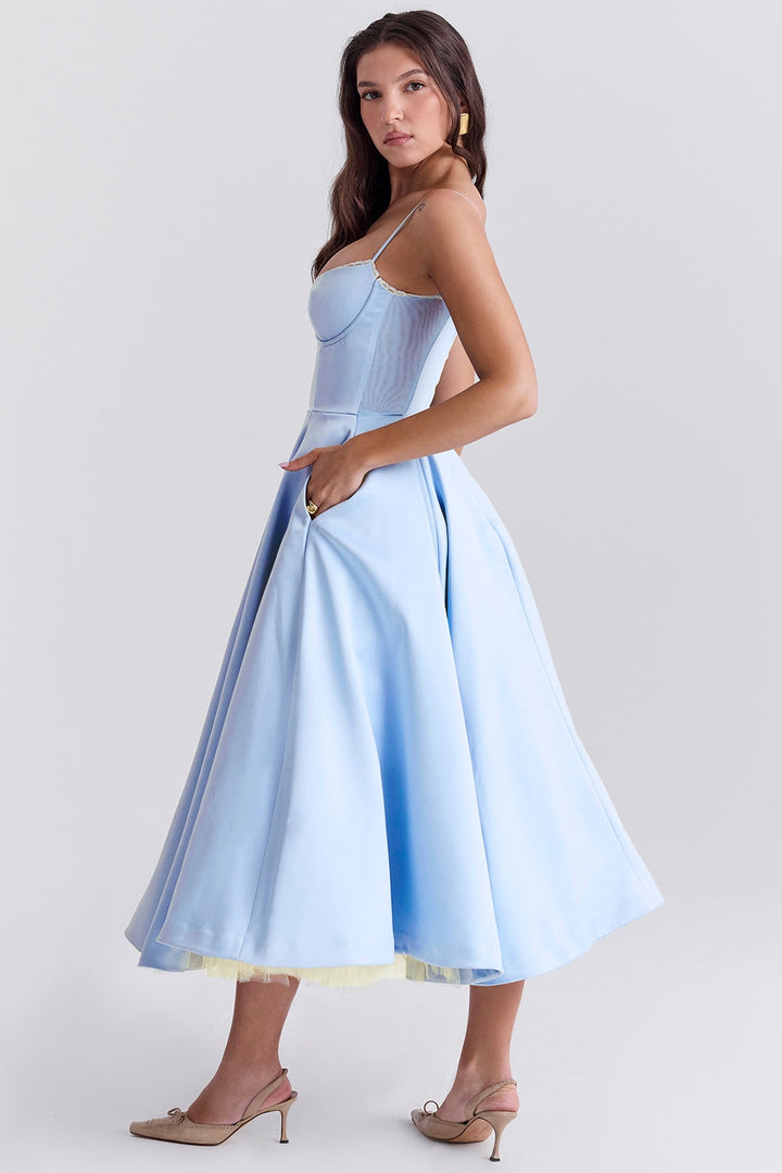 Frau in hellblauem, schulterfreiem Kleid mit weitem Rock und Spaghettiträgern, seitlich stehend, elegante Mode, Sommerkleid, stilvoll.