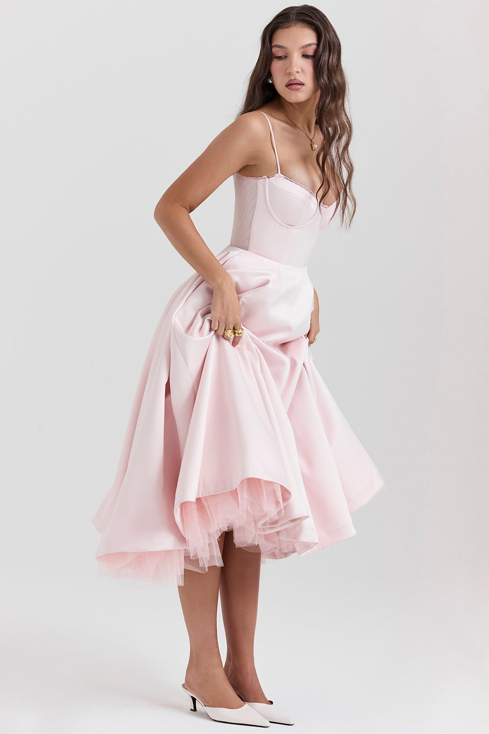Frau in rosa Cocktailkleid mit Korsett-Oberteil und weitem Rock, posiert elegant. Mode, Abendkleid, feminine Eleganz, stilvolle Kleidung.