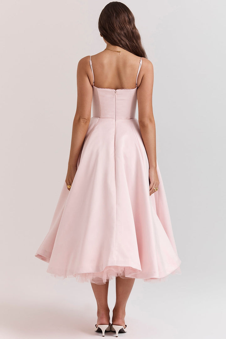 Frau in rosa Abendkleid mit Spaghettiträgern, Rückansicht. Elegantes, knielanges Design, ideal für Hochzeiten oder formelle Anlässe.