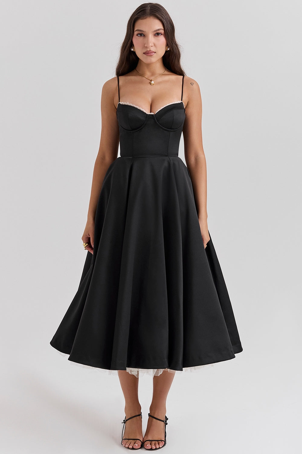 Frau in elegantem schwarzen Abendkleid mit Spaghettiträgern und ausgestelltem Rock, ideal für formelle Anlässe. Elegante Mode, Abendgarderobe.
