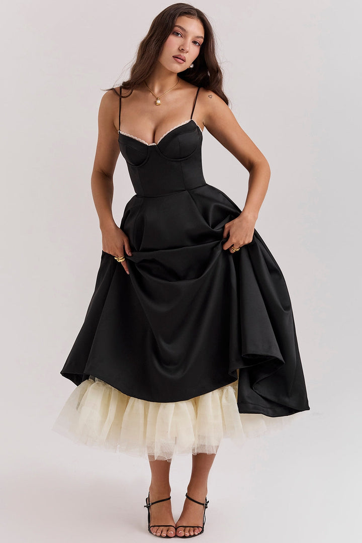 Frau in elegantem schwarzen Abendkleid mit Spaghettiträgern und Tüllunterrock, posiert vor neutralem Hintergrund. Mode, Abendgarderobe, Damenkleidung.